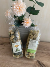 Zwei Tüten Aloe Vera Gold Wellness Pasta von vorne und hinten, daneben ein Blumenstrauß